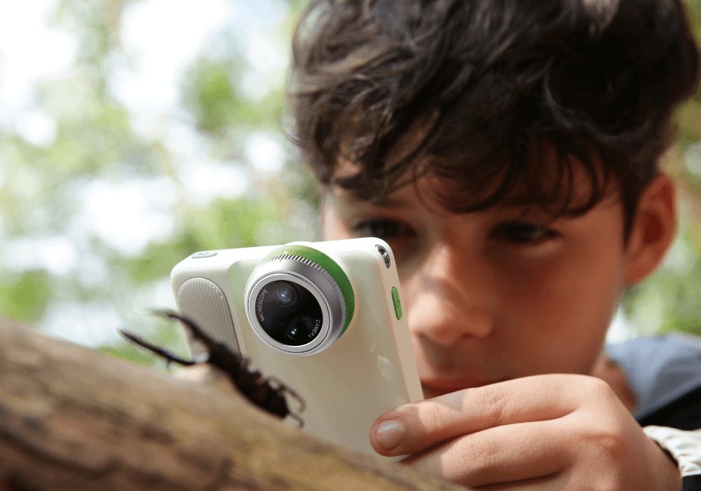 Boy using Littpopo MicroCam X1 to photograph insect in nature.